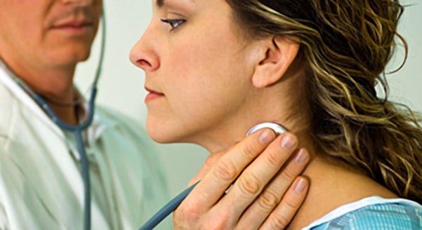 doctor checking womans throat for thyroid